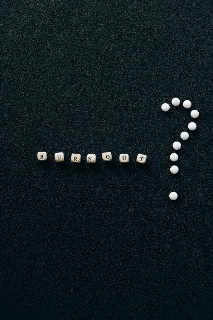 A visual representation of burnout and questioning with beads forming words and symbols on a textured black surface.
